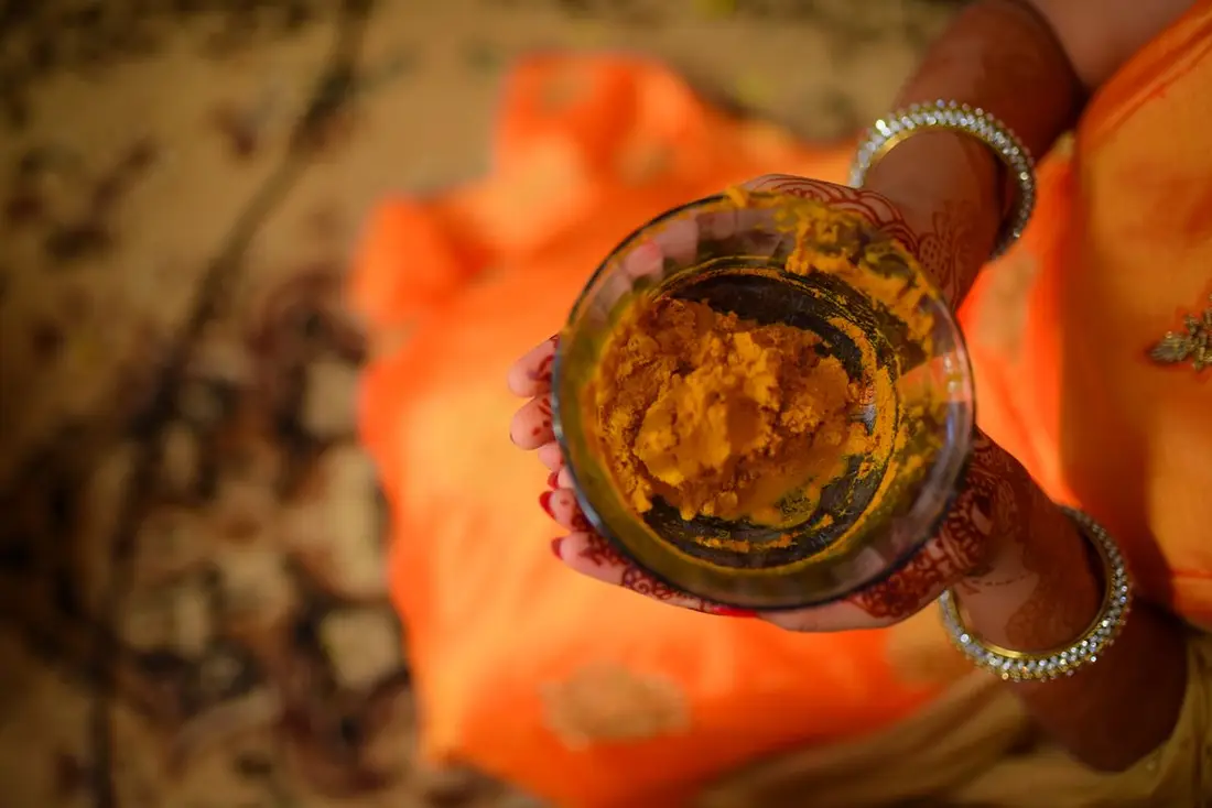 Bowls of turmeric paste and loose marigolds set out for the haldi